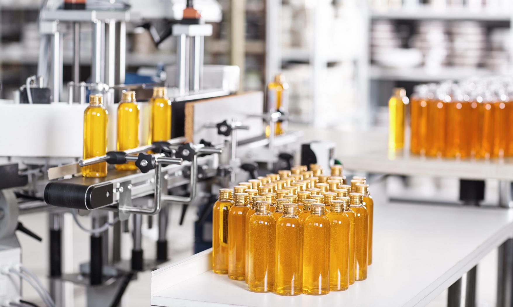 Cosmetics factory. Bottling line filled with yellow shampoo. Aut